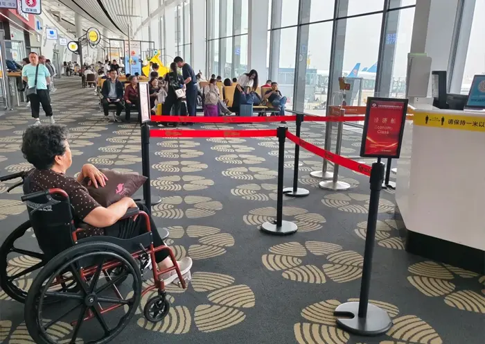 Pasajera en silla de ruedas esperando en la zona de embarque de un aeropuerto en China
