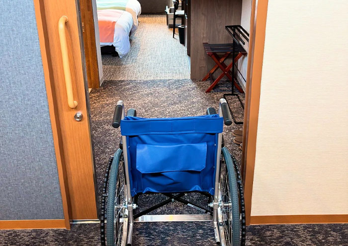 Vista desde la entrada de una habitación de hotel accesible adaptada para silla de ruedas con puertas anchas y barras de apoyo